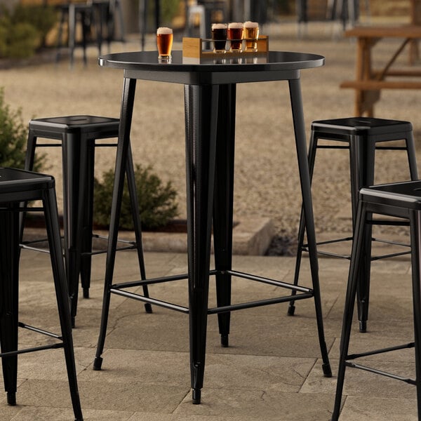 A Lancaster Table & Seating black metal bar height table with black chair legs.