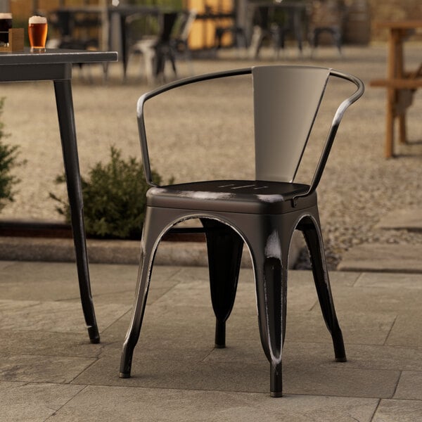 A Lancaster Table & Seating black metal outdoor arm chair on a patio.