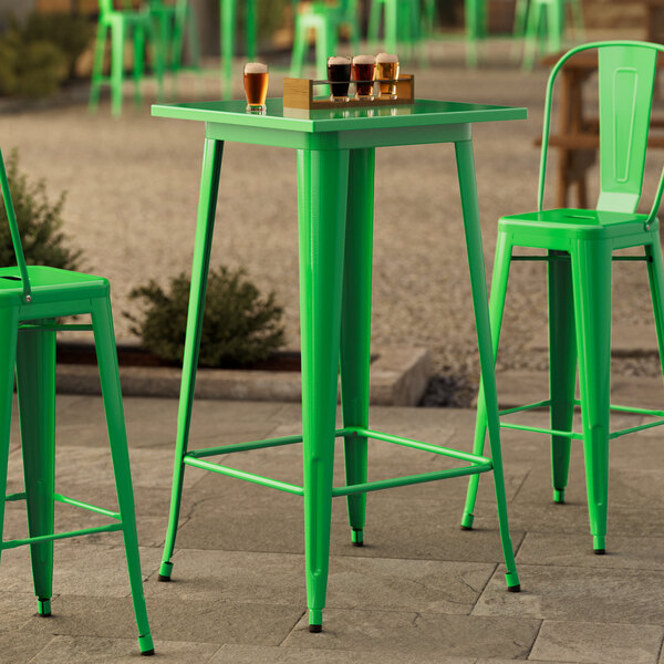 A Lancaster Table & Seating jade green bar height outdoor table with a green pole in the middle.