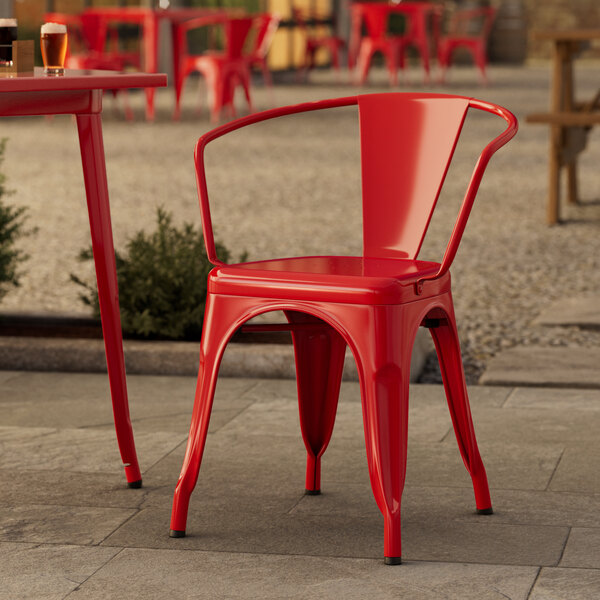 A Lancaster Table & Seating Ruby Red outdoor chair on a stone patio.