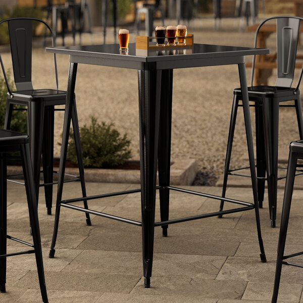 A Lancaster Table & Seating black metal table with a glass of beer on it.