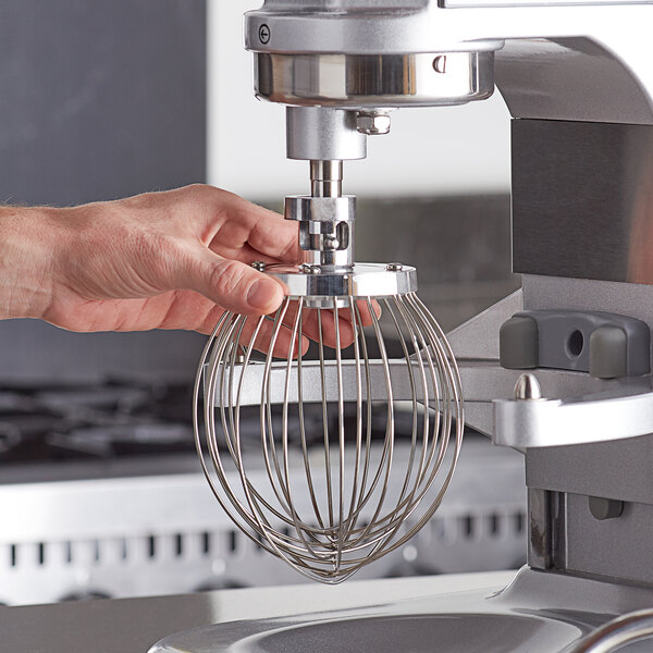 A person using an Estella wire whisk attachment on a mixer.