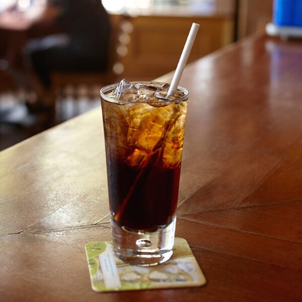 A glass of brown liquid with ice and an Aardvark white paper straw.