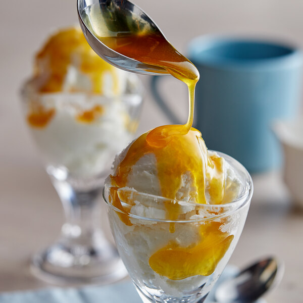 A spoon pouring J. Hungerford Smith Butterscotch Topping over a dessert.