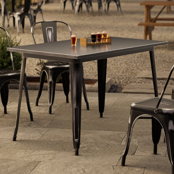 A Lancaster Table & Seating outdoor table with chairs and glasses of beer on a patio.