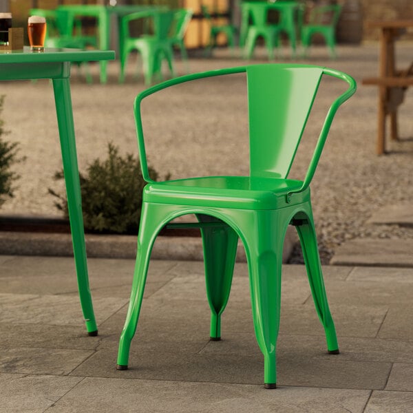 A green Lancaster Table & Seating outdoor arm chair on a stone patio.