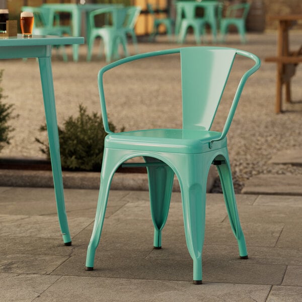 A Lancaster Table & Seating aquamarine chair on an outdoor patio.