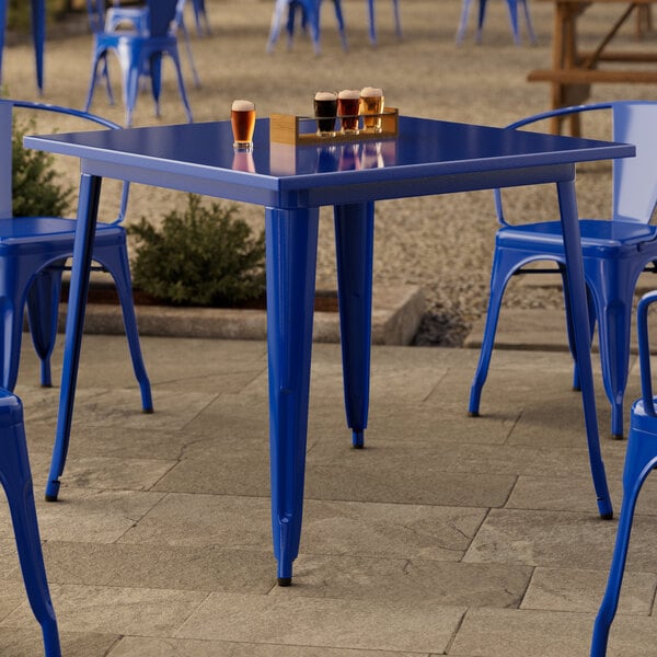 A blue Lancaster Table & Seating outdoor table with glasses of beer on it.