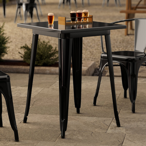 A Lancaster Table & Seating black metal table with drinks on it on an outdoor patio.