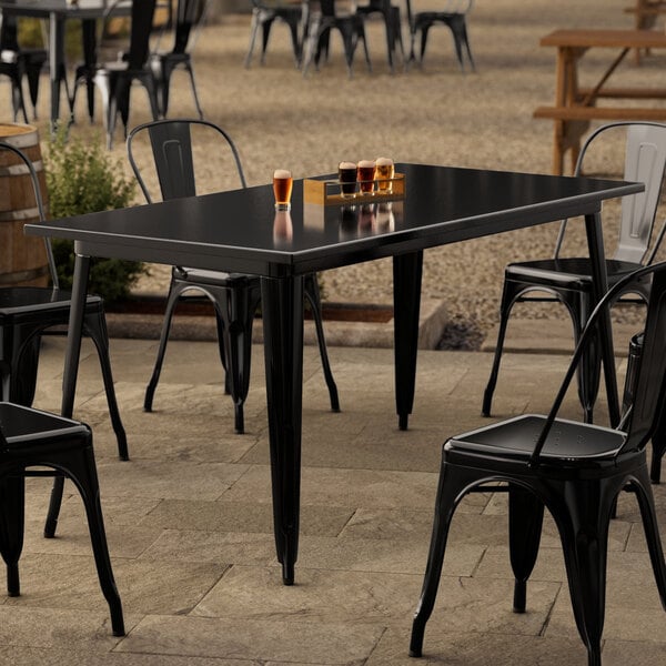 A Lancaster Table & Seating Onyx Black outdoor table with chairs on a patio.