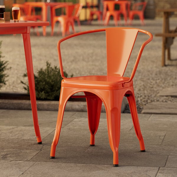 A Lancaster Table & Seating amber orange chair on an outdoor patio.