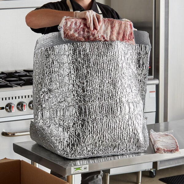 A woman using a Lavex insulated box liner to hold a piece of meat.