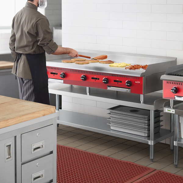 A man cooking on an Avantco Chef Series countertop gas griddle in a professional kitchen.