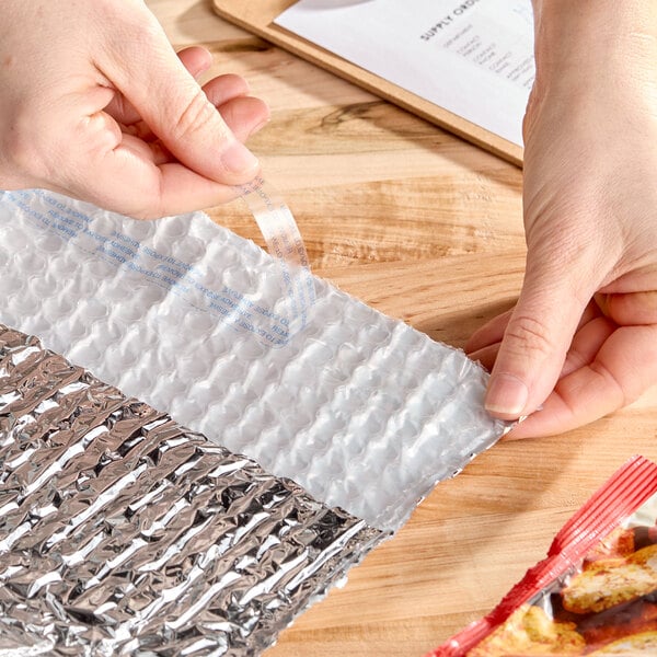 An insulated box liner with a bubble wrap interior and foil exterior being prepared for use.