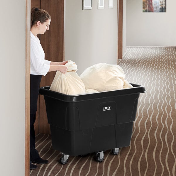 A woman pushing a large white bag into a black Lavex cube truck.