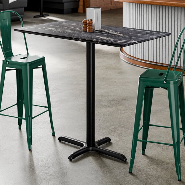 A rectangular bar height table with a smooth black finish and a cross base plate.