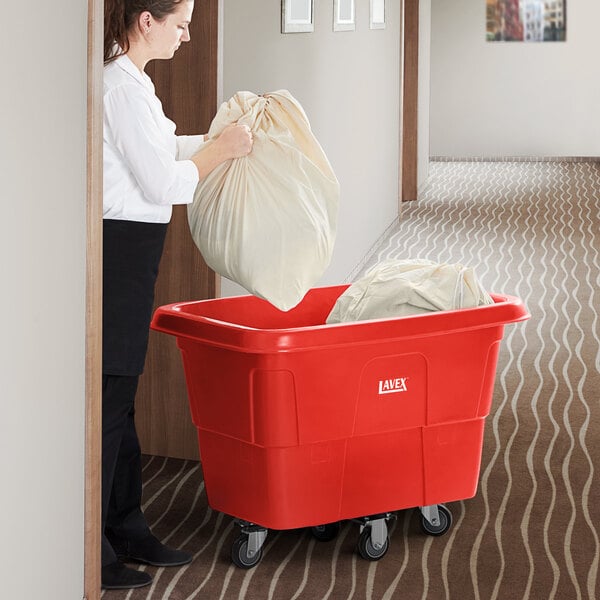 A woman putting a large white bag into a red Lavex cube truck.