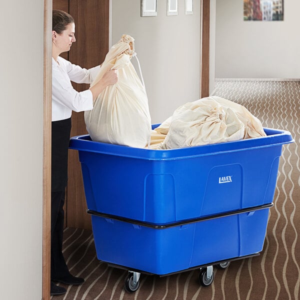 A woman pushing a large white bag into a blue Lavex cube truck.