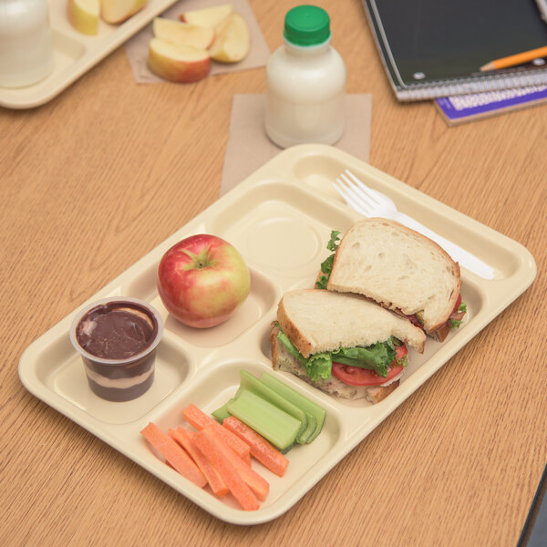 A Carlisle tan melamine 6 compartment tray with a sandwich, apple, and carrot.