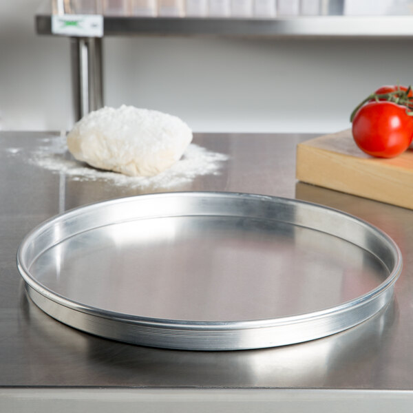 An American Metalcraft heavy weight aluminum pizza pan on a counter.