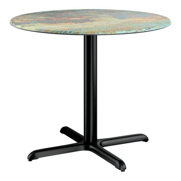 A round standard height table with a textured canyon painted faux metal finish top and a black cross base plate.