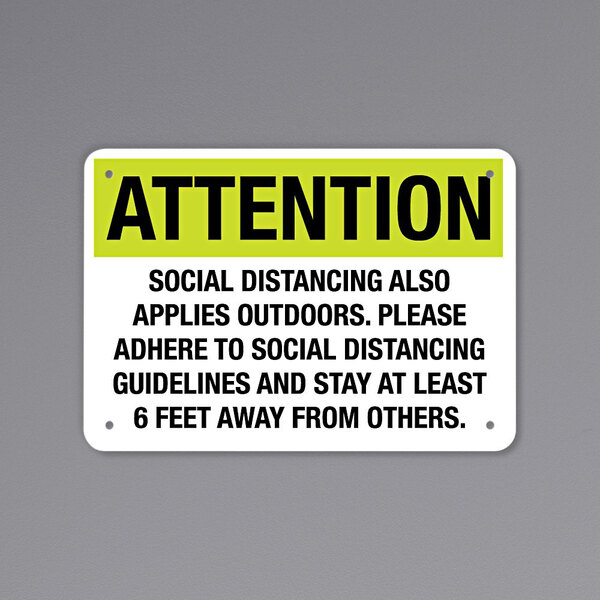 A black and yellow rectangular decal with the words "Attention Social Distancing Also Applies Outdoors" in black and white text.