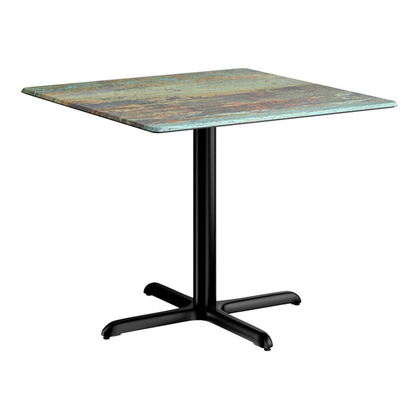 A square standard height table with a textured canyon painted faux metal finish top and a black cross base plate.