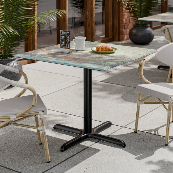 A square standard height table with a textured canyon painted faux metal finish and a black cross base plate.