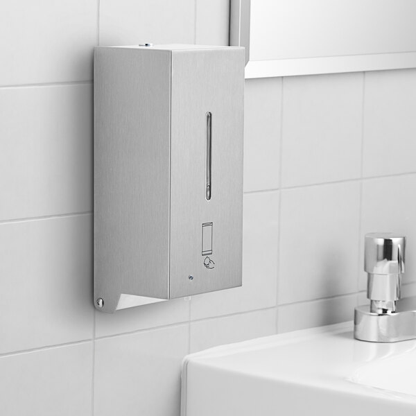 A silver Bobrick stainless steel automatic soap dispenser on a white tile wall.