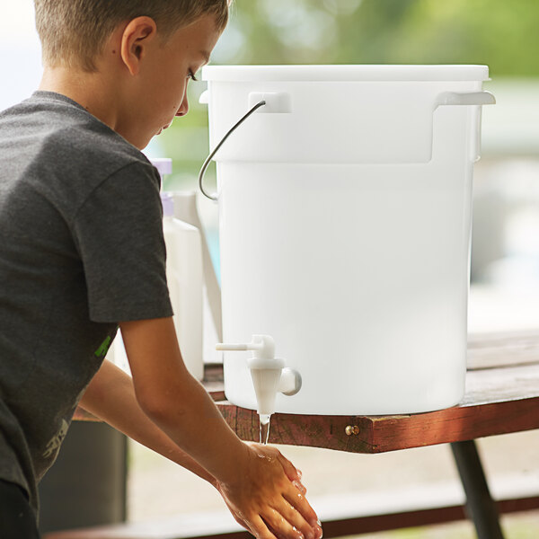 A boy washing his hands in a white Choice round dispenser.