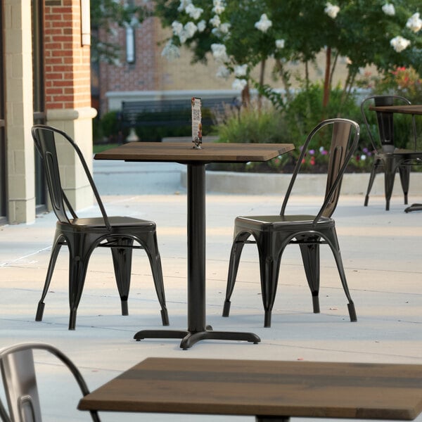 A Lancaster Table & Seating Excalibur wood table with a cross base on a patio.