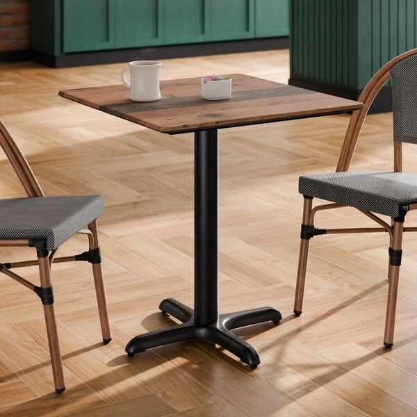 A square standard height table with a textured farmhouse finish and a black cross base plate.