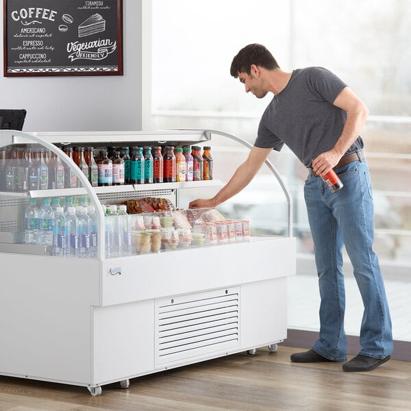 A man standing in front of a white Avantco horizontal air curtain merchandiser.