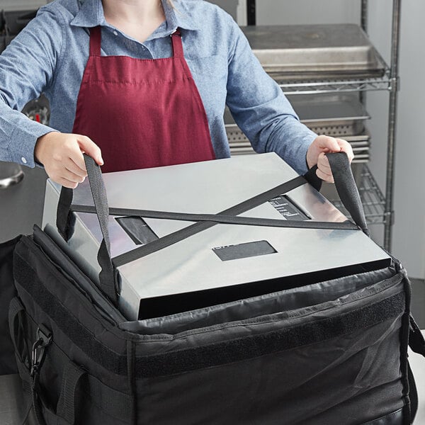A person in a red apron using a Vesture aluminum shelf to carry a large box with a strap around it.