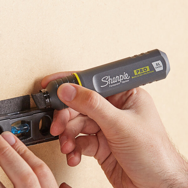 A hand using a Sharpie Pro Black Broad Chisel Tip Marker to fill a wall.