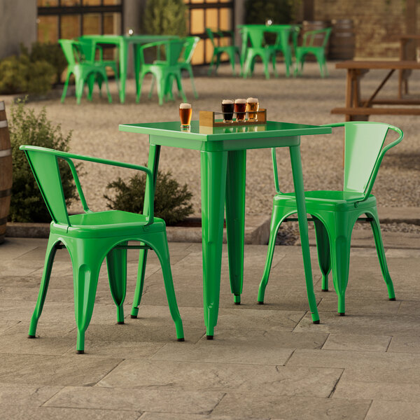 A jade green Lancaster Table & Seating outdoor table with chairs on a stone patio.