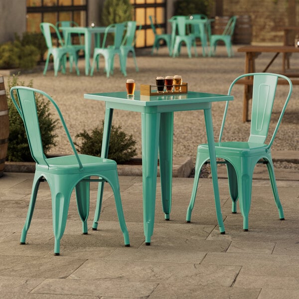 A Lancaster Table & Seating outdoor table with green chairs on a patio.