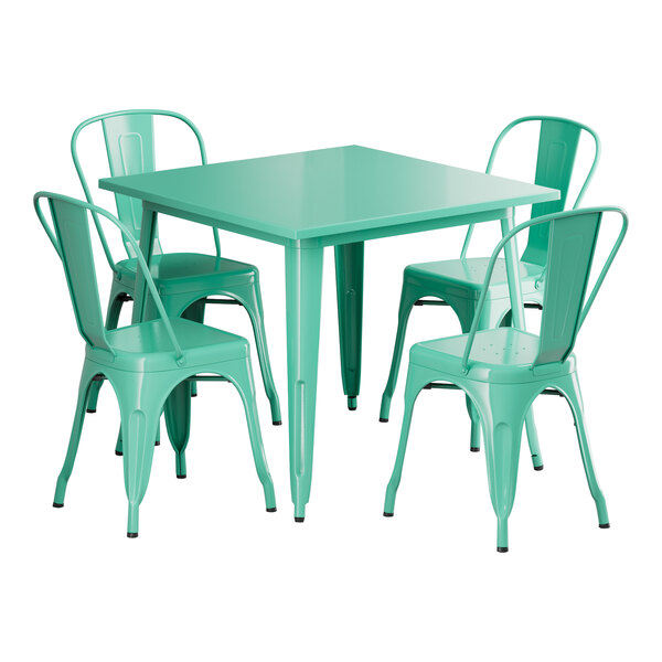 A Lancaster Table & Seating outdoor table with an aquamarine top and white legs with four green chairs around it.