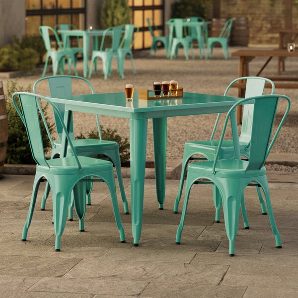 A Lancaster Table & Seating aquamarine table with four chairs on an outdoor patio.