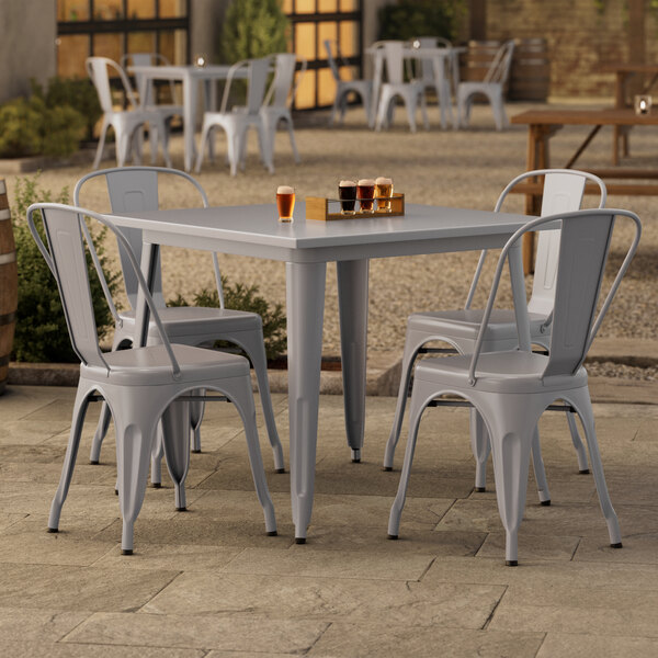 A Lancaster Table & Seating outdoor table with four chairs on a patio.