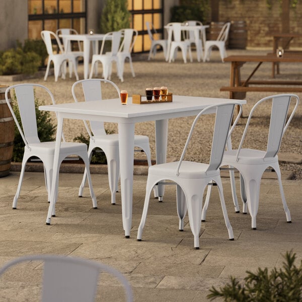 A Lancaster Table & Seating pearl white table with four chairs on an outdoor patio.