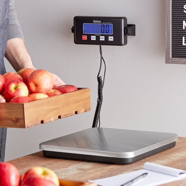 A person weighing apples on a Galaxy RS220LP low-profile digital receiving scale.