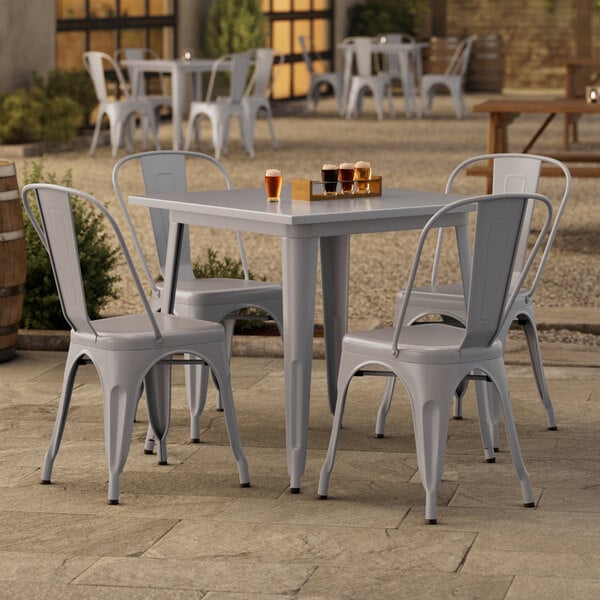 A Lancaster Table & Seating outdoor table with four chairs on a patio.