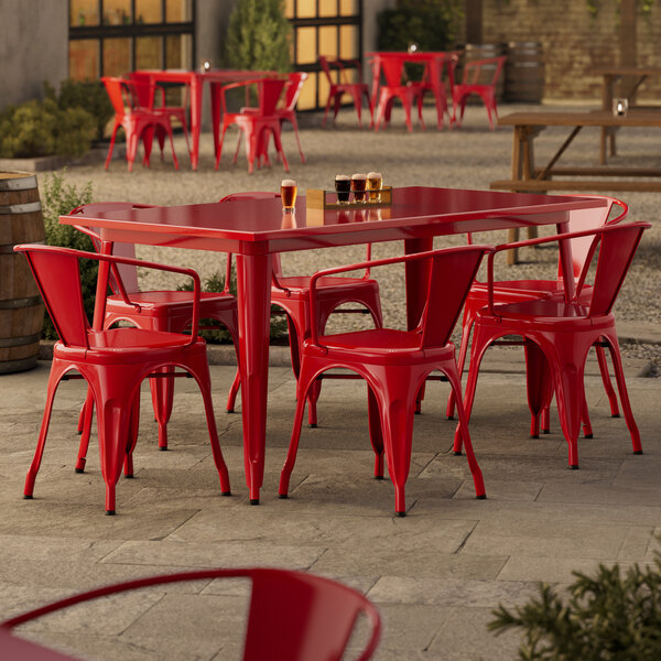 A Lancaster Table & Seating ruby red table with chairs on a stone patio.