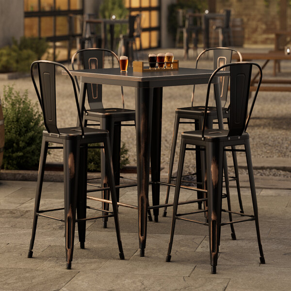 A Lancaster Table & Seating outdoor bar table with four distressed copper barstools.