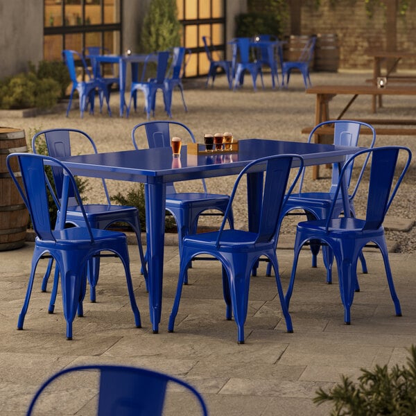 A blue Lancaster Table & Seating outdoor table with six chairs on a concrete patio.