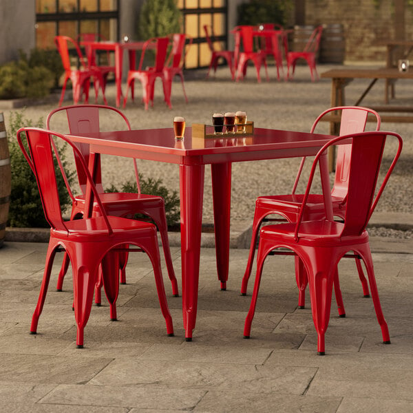 A Lancaster Table & Seating ruby red table with 4 chairs on a patio.