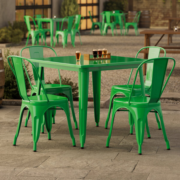 A jade green table with chairs outside on a patio.