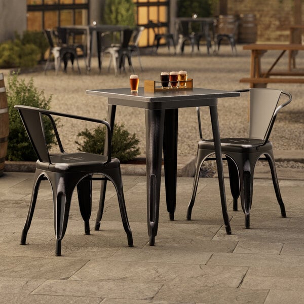 A Lancaster Table & Seating black metal table and chairs on an outdoor patio.