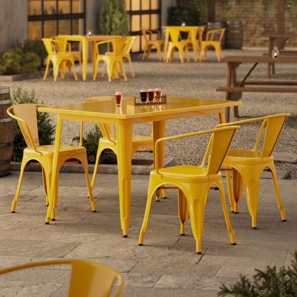 A Lancaster Table & Seating citrine yellow table and chairs sitting outside on a patio.